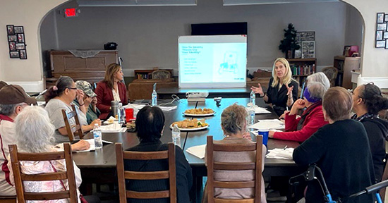 Seniors sitting at a conference table with a presenter at Pisgah Village